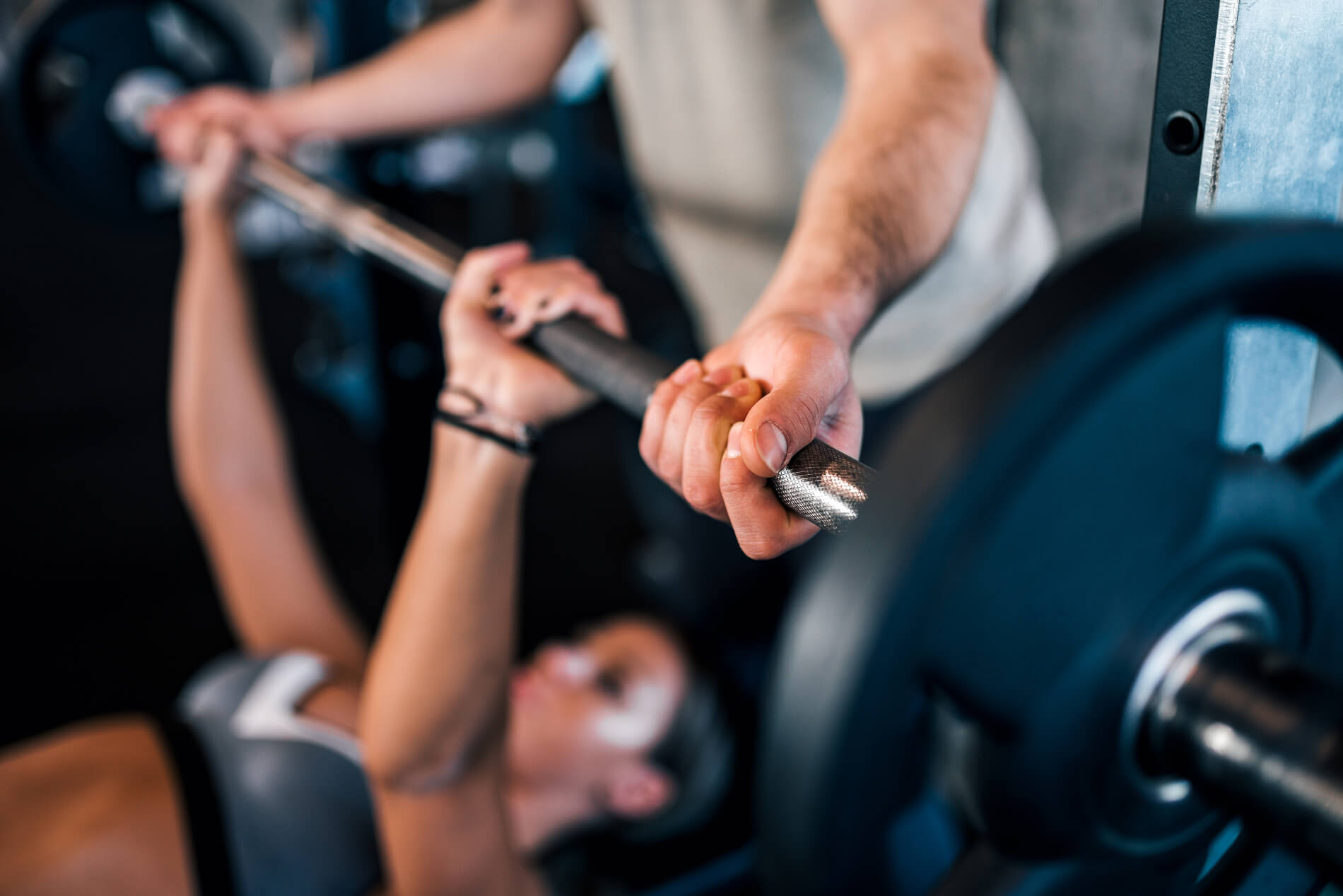 Woman lifting weights with spotter in gym