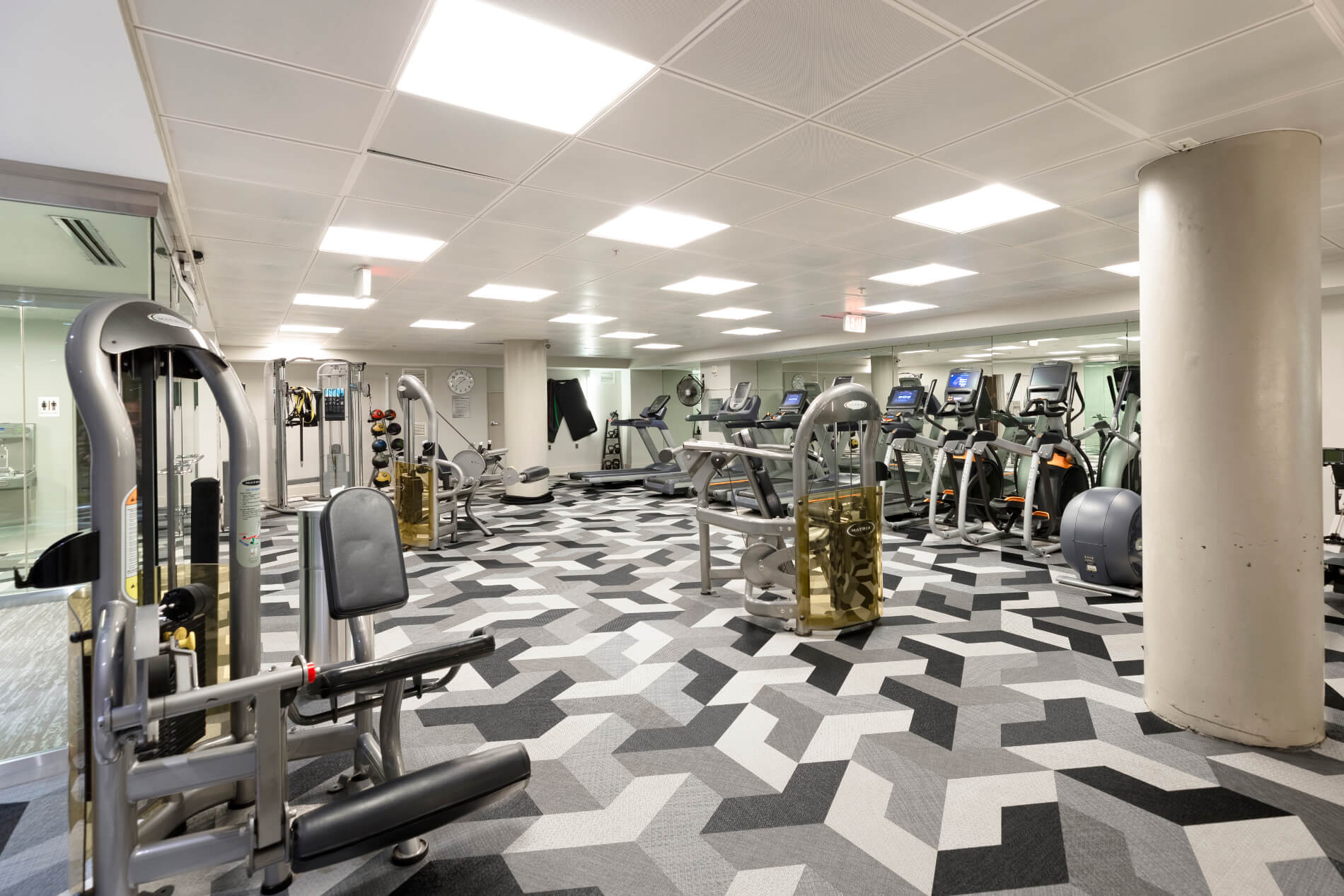 Gym with workout equipment, ceiling lights and patterned flooring