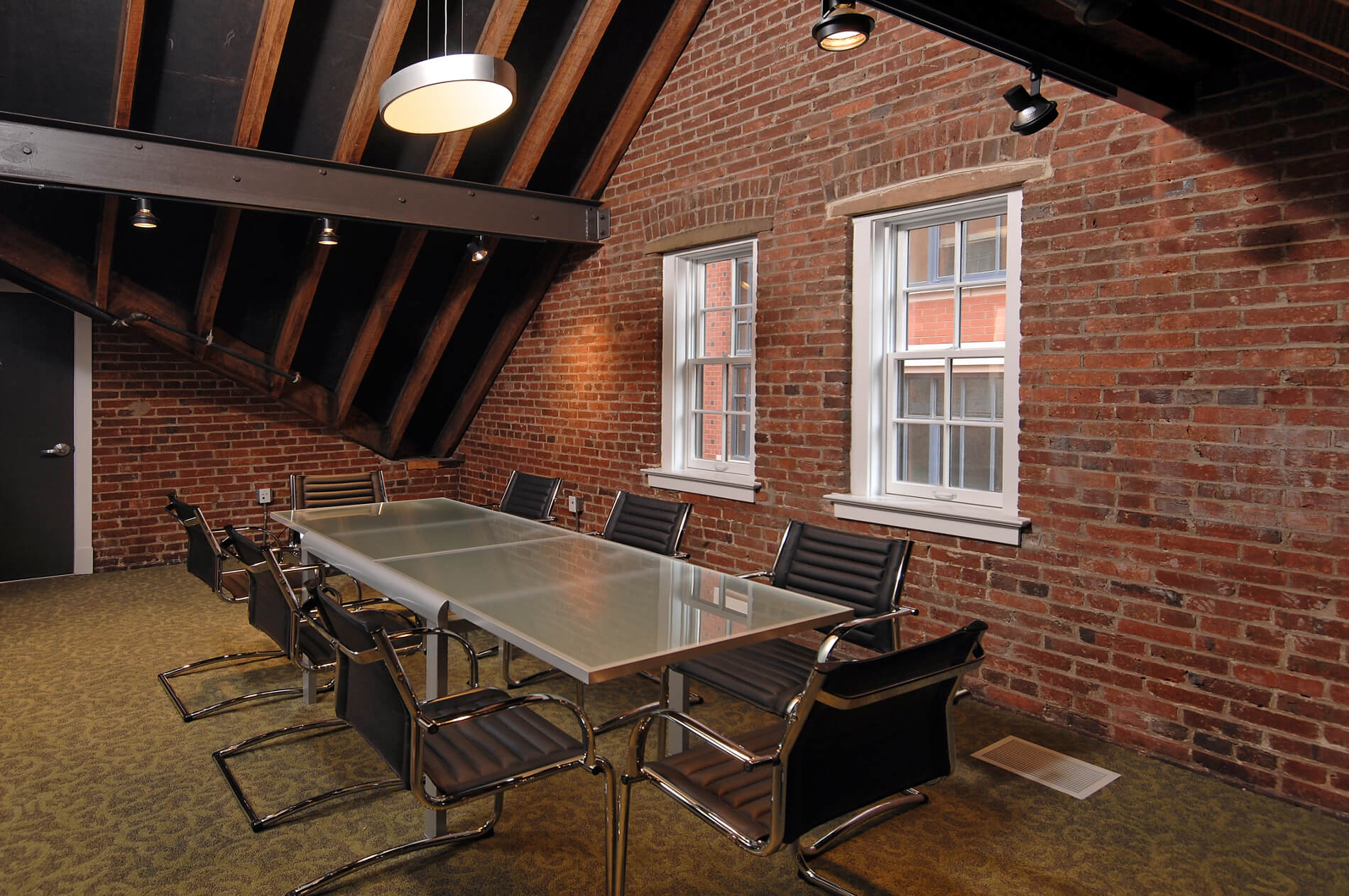 Table with eight chairs in brick room with exposed wooden rafters