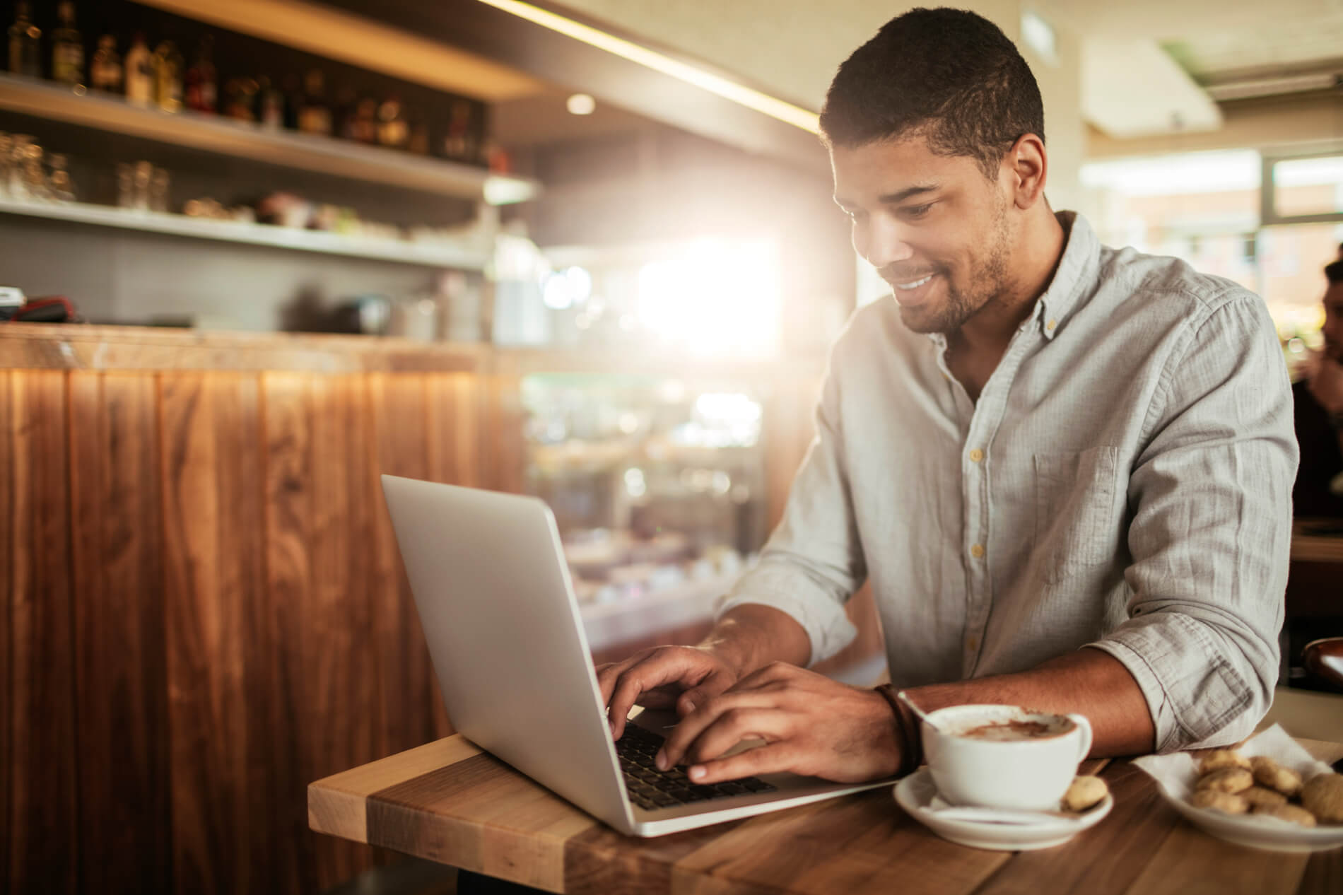 Man working on laptop with coffee and pastries in coffee shop